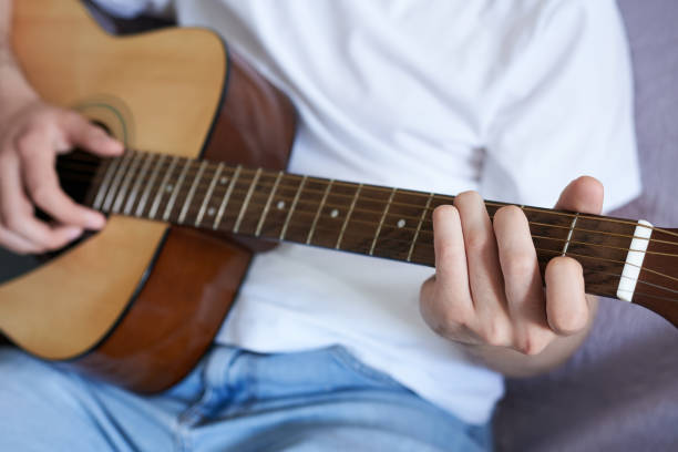 istock A man playing an acoustic guitar on a sofa. Concept of musical instruments 2178477936