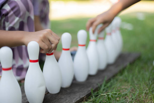 istock Two people are playing with white plastic bowling pins on a wooden board 2178478459