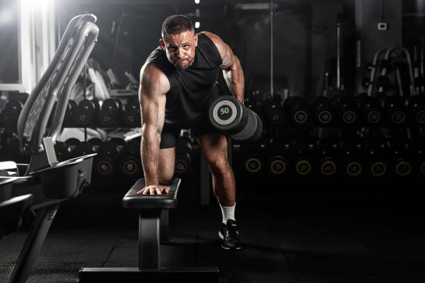 istock Muscular man training with weights. Brutal strong athletic men pumping up muscles workout in dark gym. 2178481784