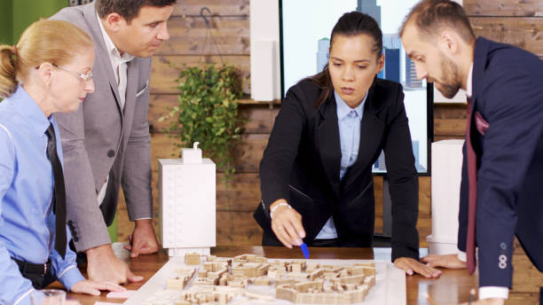 istock Female architect in the conference room pointing at mini town 2178481854