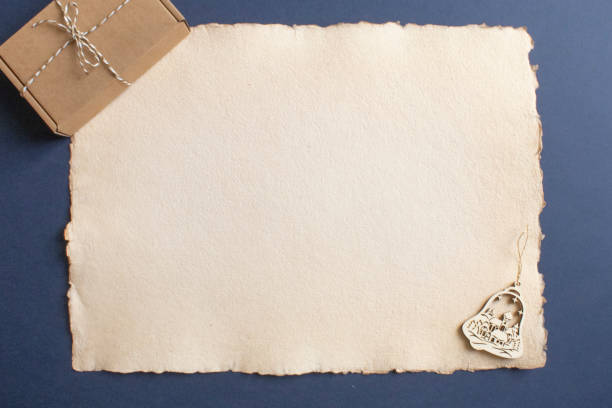 A holiday-themed flat lay featuring a brown gift box tied with twine and Christmas ornament. The items are placed on a paper sheet over a navy blue background, reflecting a minimalist, rustic style.