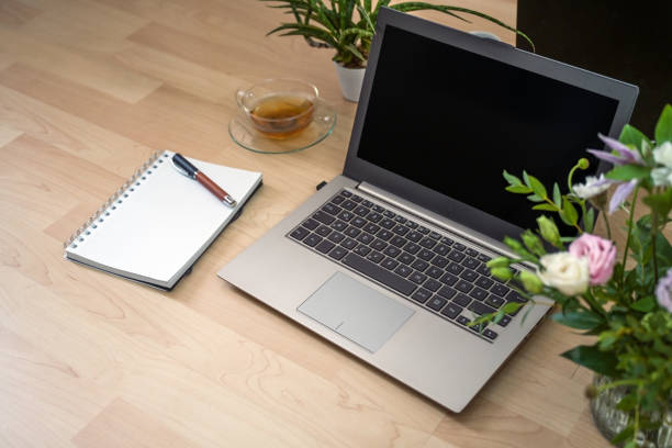 istock Laptop on a wooden desk, notebook, pen, tea and flowers, workplace for freelancer, study or home office, copy space, selected focus 2178483675
