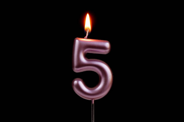 Number 5 Candle On Birthday Cake Against Yellow Background
