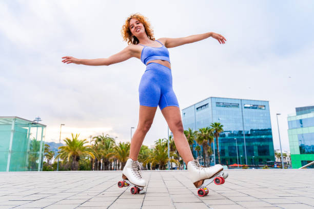 Beautiful red haired young woman with rollerskates having fun outdoors - Pretty female teenager girl with unique style riding on roller skates in the city