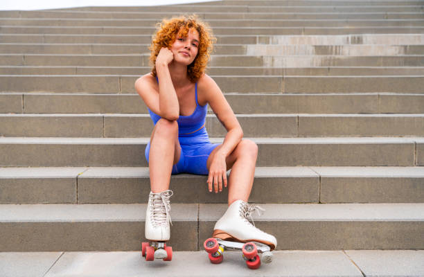 Beautiful red haired young woman with rollerskates having fun outdoors - Pretty female teenager girl with unique style riding on roller skates in the city