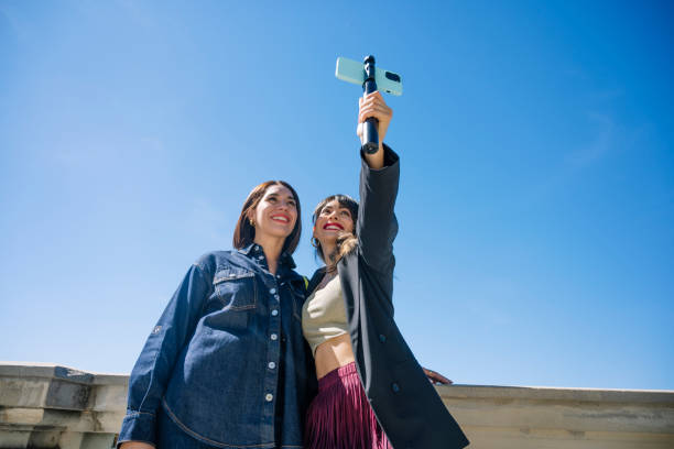 istock Two women posing outdoors, taking a selfie together with blue skies in a sunny environment. 2178486903
