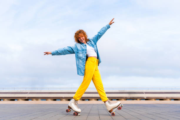 Beautiful red haired young woman with rollerskates having fun outdoors