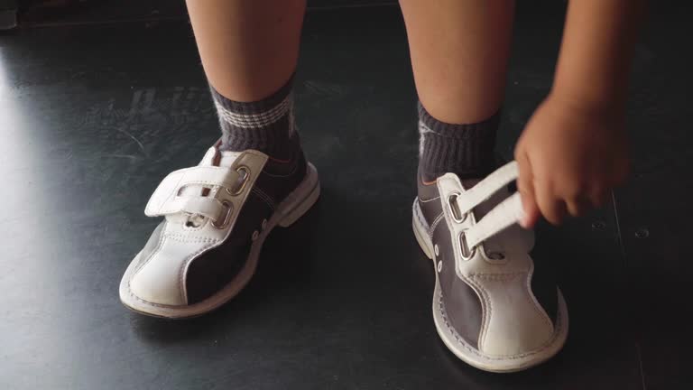 kid fastening his bowling shoes and dancing before the game