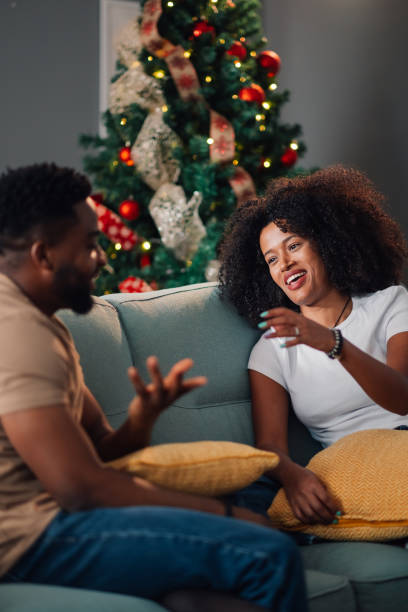 istock Happy african american couple conversing on couch with Christmas tree behind 2178496973