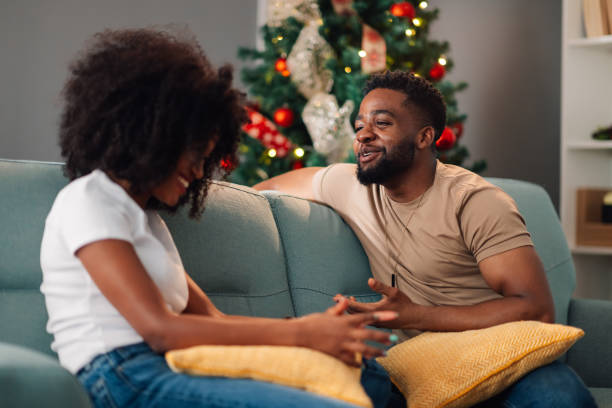 istock African American couple sitting together on a sofa with Christmas tree 2178496983