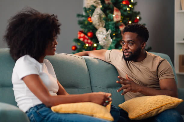 istock African american couple talking on sofa with Christmas tree in background warmly 2178496990