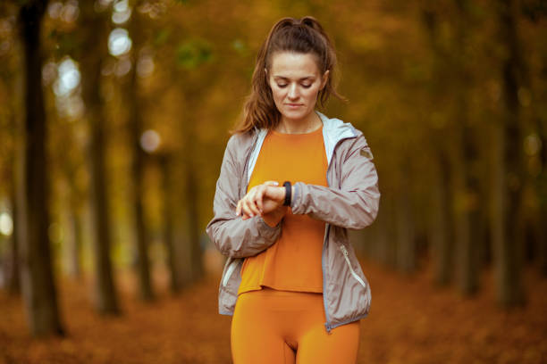 trendy woman in fitness clothes in park fit tracker stock photo