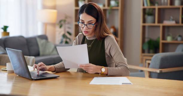 istock Paperwork, reading or woman on laptop in remote work with documents for online banking, finance or taxes. Home, bookkeeping or female accountant with report for budget, financial review or planning 2178500638