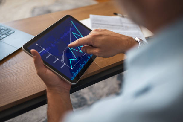 istock Man reviewing financial data on tablet at home with documents nearby 2178501169