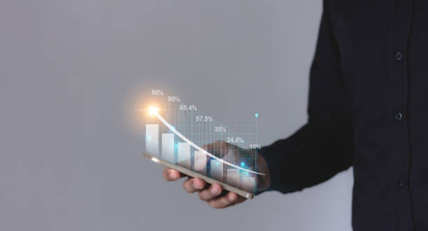 istock Young man hand using smartphone to visualize money growth The phone screen displays graphs and charts showing increasing investment and savings trends, along with an increased account balance 2178502196