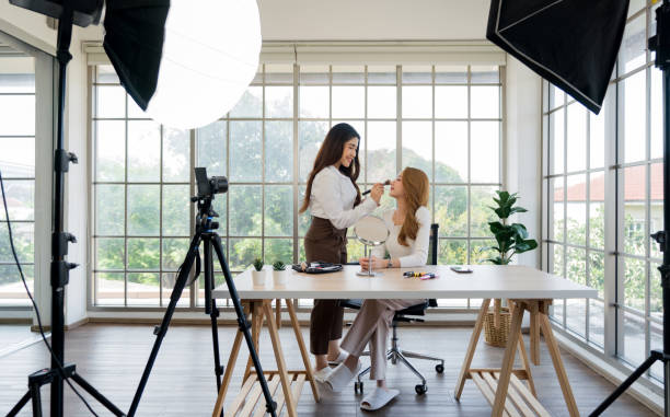 istock Two asian women creating content for social media. They are using a studio setup that include a camera mounted on a tripod, lighting equipment and various makeup product on the table. 2178502264