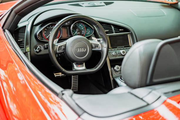 Horizontal street photo. Fragment of red, scarlet, crimson sport convertible car against background of mountain, hill. Windshield, rearview mirror, seat. Concept of transport, travel, tourism, rent