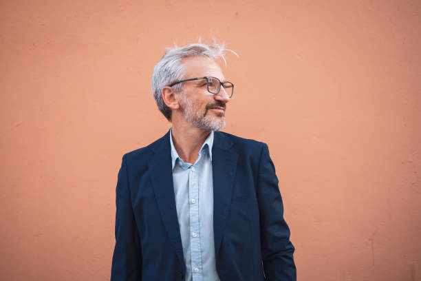 istock Stylish mature man in a suit against an orange wall background 2178507038