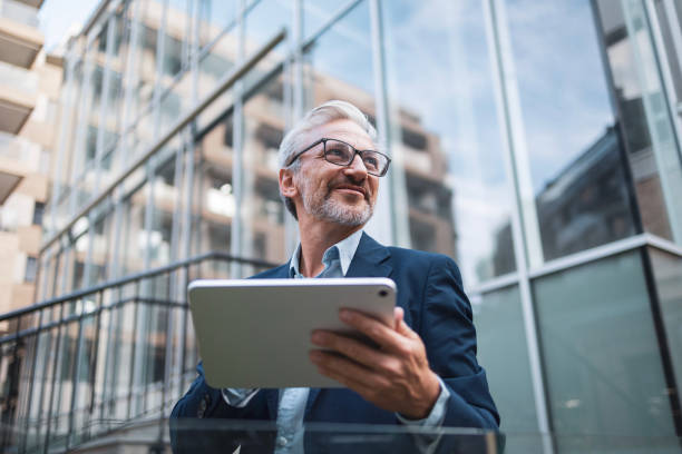 Confident businessman with tablet at modern glass office building