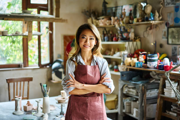 istock Pretty female artist smiling and posing at creative workshop with her artwork in the background. 2178507769