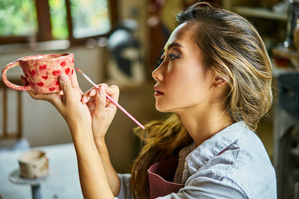 istock Female artist decorating and painting handmade ceramic clay cup at her creative workshop 2178507787