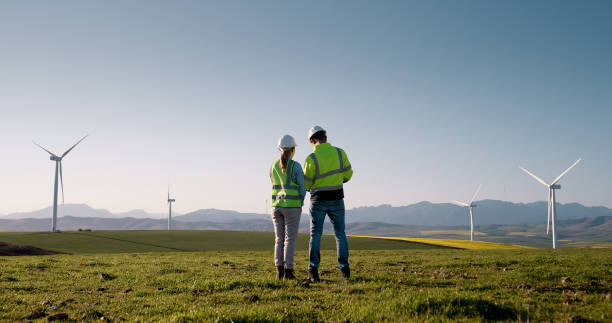 istock Business people, back and electrical engineers with wind turbine for clean energy, renewable power or reproduction system. Man, woman or contractors with eco friendly resources for carbon capture 2178507807