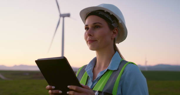 istock Wind energy, engineer or thinking in field with tablet, PPE or happy for eco friendly power development with space. Woman, windmill farm or tech with smile, inspection or renewable resource 2178507896
