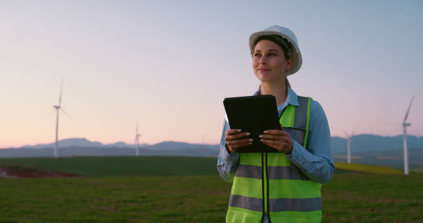 istock Wind energy, woman or thinking in field with tablet, PPE or happy for eco friendly power development with space. Engineer, windmill farm or tech with smile, inspection or renewable resource 2178507921