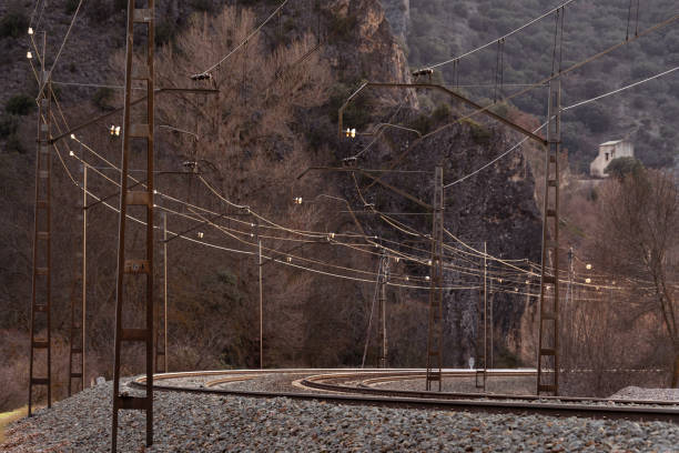 Steep curve of railroad tracks and installation of a catenary along its trajectory.