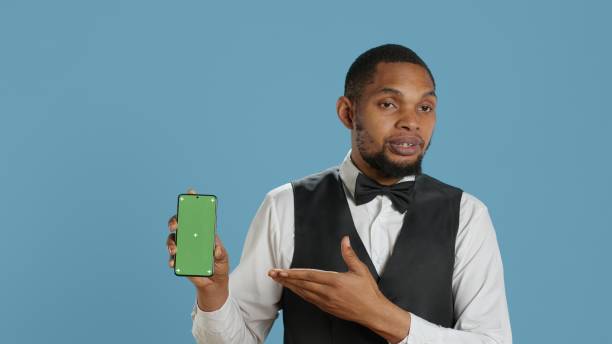 istock Hotel worker bellhop points at phone with isolated mockup display 2178511359