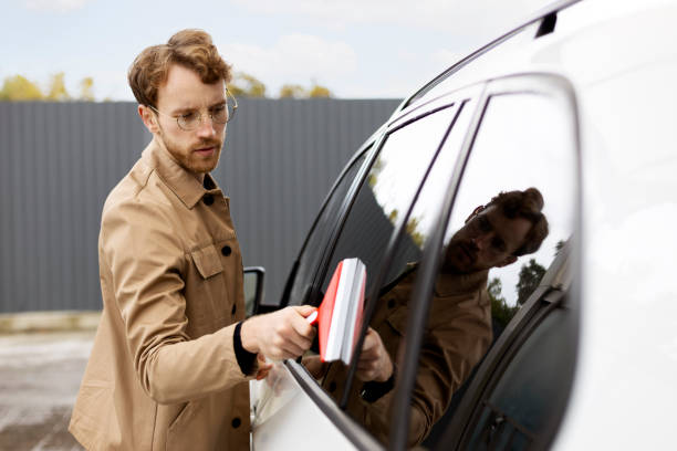 istock Young man cleaning his car with a squeegee outdoors 2178511433