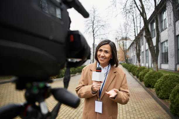 istock Journalist in a coat interviews on microphone in urban park setting during chilly afternoon 2178511504