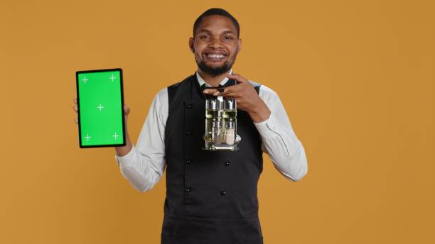 istock Restaurant staff showing tablet with green screen against yellow background 2178511646