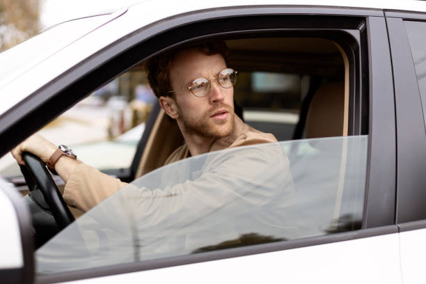 istock Stylish man with glasses driving a car looking away 2178511670