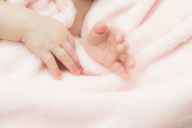 Adorable baby in white sunny bedroom. Newborn child relaxing in bed. Nursery for young children. Textile and bedding for kids. Family morning at home. New born kid on rainbow blanket.