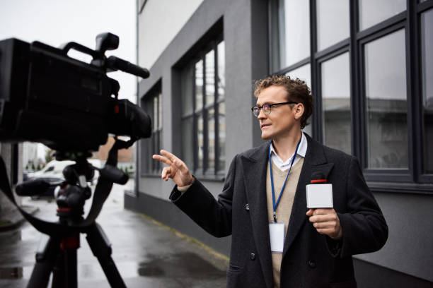 istock Professional journalist in glasses conducts an interview outdoors with a camera setup nearby 2178511907