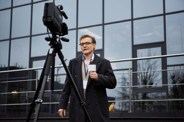 istock A journalist in glasses reports live outside a modern building on a cloudy afternoon 2178512142