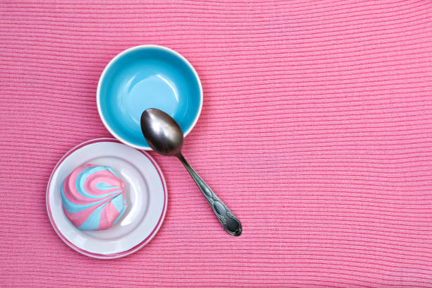 Colorful fluffy marshmallow on saucers on a pink knitted background, close-up, flat lay, top view, horizontal, copyspace right