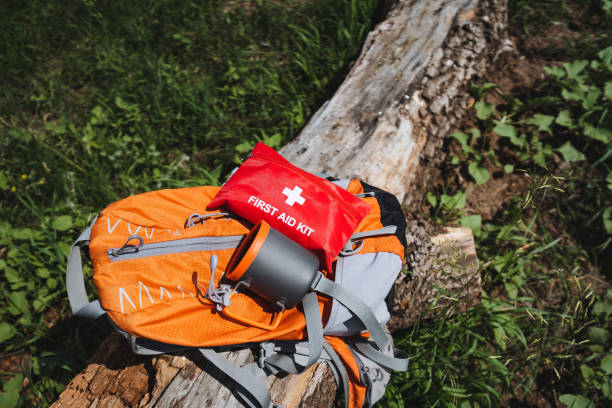 istock In a serene natural landscape, an orange backpack with a first aid kit is visible among trees and grass. The setting includes a variety of plants, creating a peaceful atmosphere 2178520450