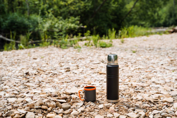 istock In a peaceful natural setting, there is a tranquil scene with a thermos and coffee cup placed on the ground among trees and grass, creating a sense of peace and serenity in the environment 2178520459