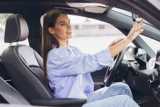 istock Young Woman Adjusting Rearview Mirror While Driving Modern Car 2178531966