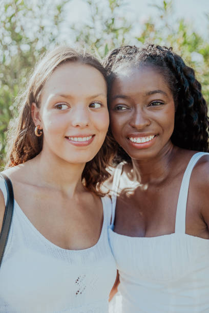 istock Two friends are smiling while standing together and looking around, female unity concept 2178534453
