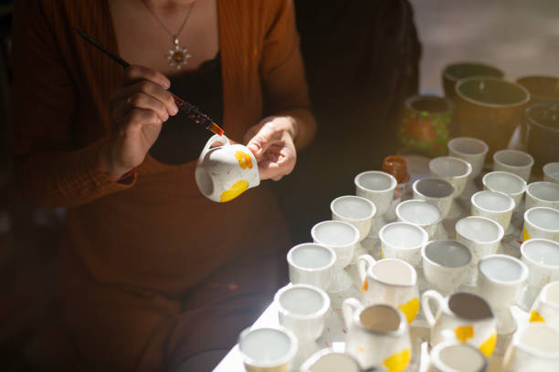 istock Female potter coloring handmade ceramic cup using brush and color. 2178536750