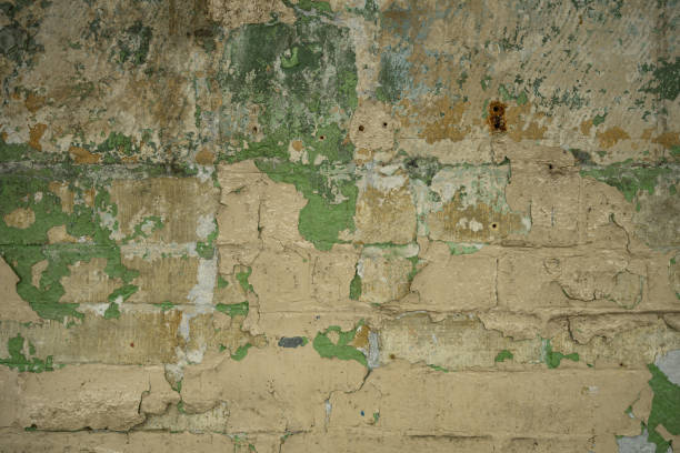 peeling paint patterns and texture on a traditional English brick building interior wall