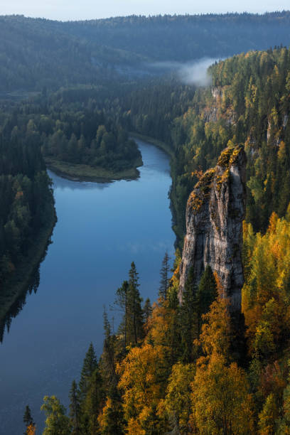 istock A tranquil river gracefully meanders through vibrant autumn foliage, flanked by majestic cliffs, as a soft mist rises in the crisp morning air 2178539022