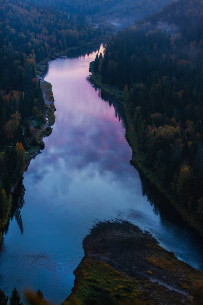 istock A winding river flows through a lush forested valley, reflecting soft twilight hues in its calm waters as the sun sets in the distance, creating a peaceful atmosphere 2178539035