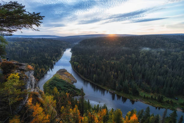 istock The sun sets behind rolling hills, casting a warm glow over a winding river embraced by vibrant autumn trees, creating a peaceful avenue of natureÐ²Ðâ¢s beauty 2178539055