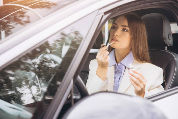 istock Elegant Woman Applying Lip Gloss in Car Interior 2178540845