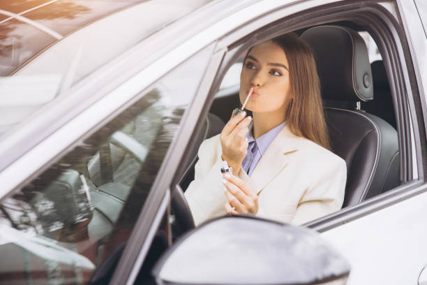 istock Stylish Woman Applying Lipstick Inside a Modern Car 2178540878