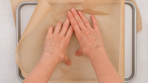 istock Woman's hands delicately place parchment paper on a baking pan, close-up 2178548380